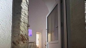 Una stanza con una parete in pietra, una porta scorrevole in vetro che dà su un'altra stanza e una televisione sullo sfondo.