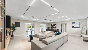 Amplia sala de estar con un sofá seccional beige, una mesa de centro y una estantería.