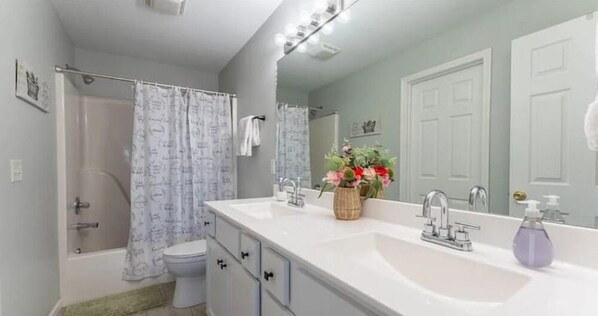 Une salle de bain avec une douche, des toilettes et un lavabo avec un miroir.