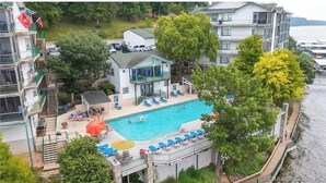 A residential building with a swimming pool, multiple balconies, and a view of the sea. - Lakefront Condo - Stunning Views (Lake Ozark)