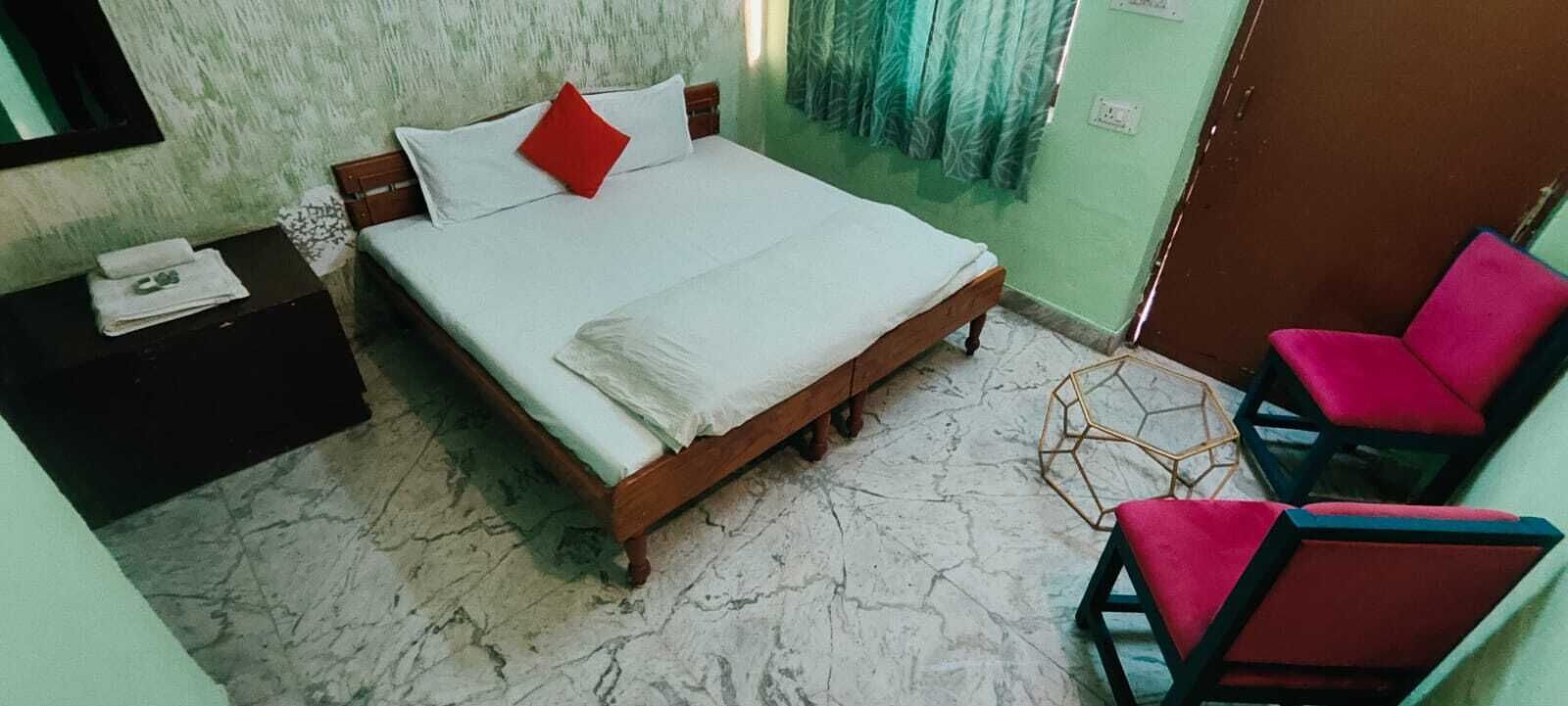A bedroom with a bed, a nightstand, a chair, and a window with curtains.