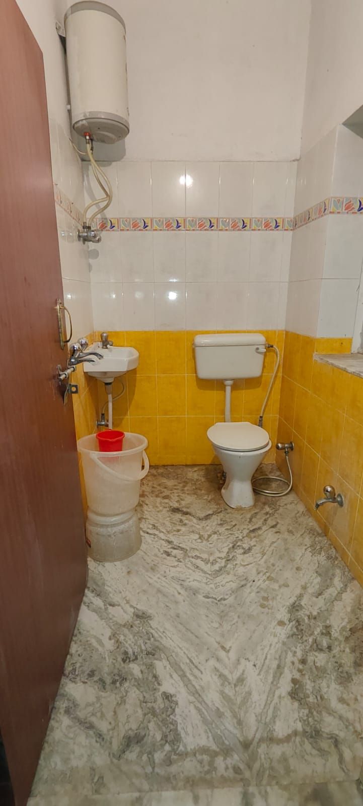 A small bathroom with a toilet, sink, and a water heater mounted on the wall.
