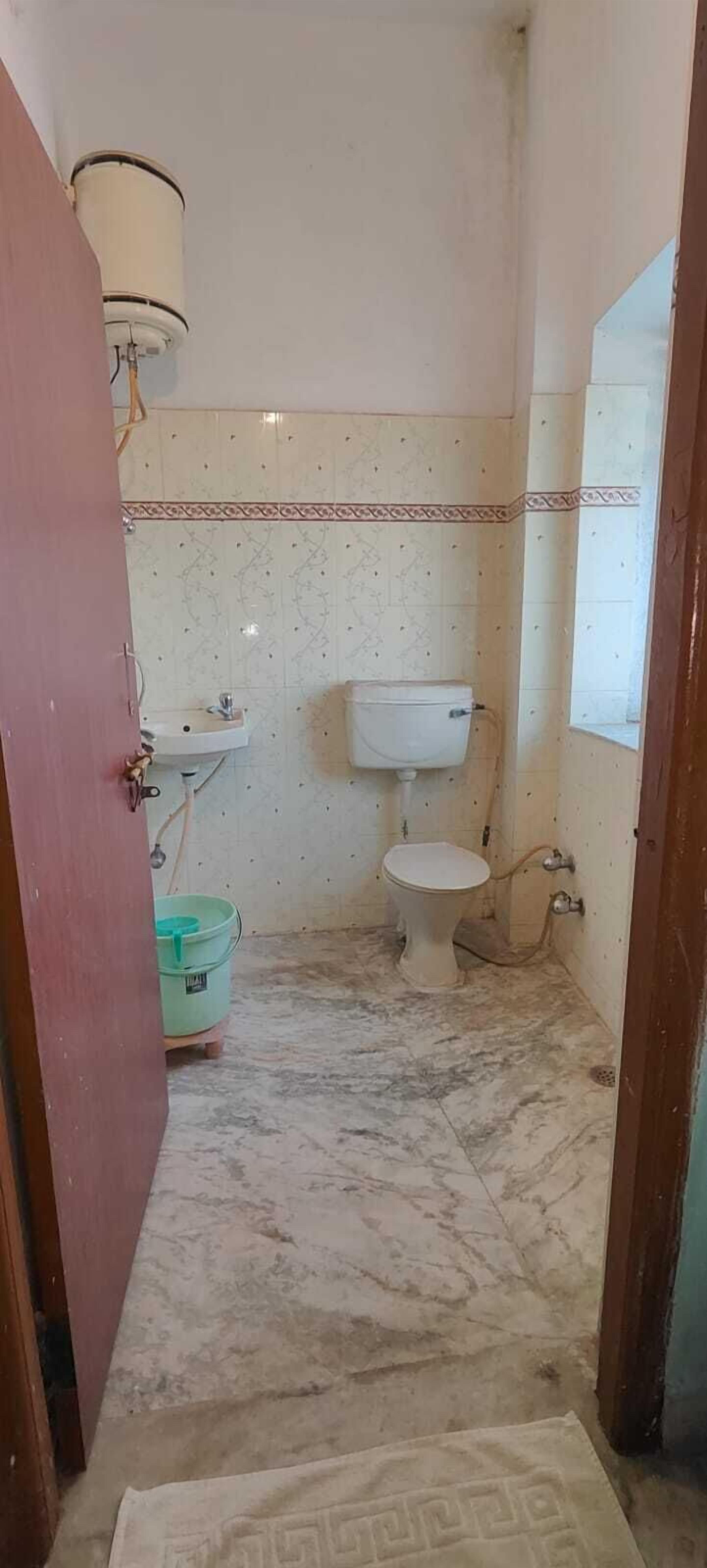 A small, compact bathroom with a toilet, sink, and a water heater.