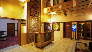 A hotel lobby with a reception desk, a decorative partition, and a ceiling fan. - Haveli Banquet & Resort (Ajmer)