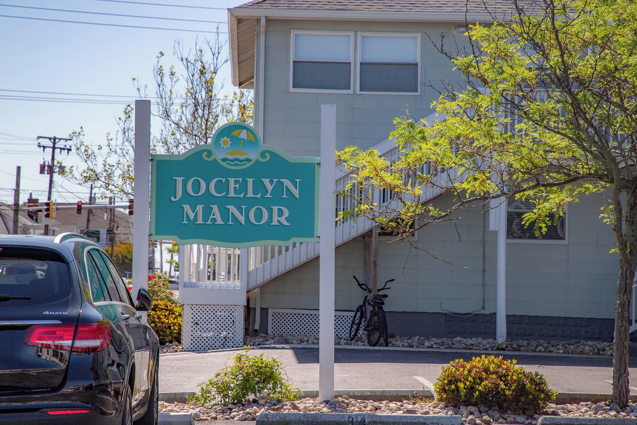 A sign for JOCELYN MANOR with a white building in the background.