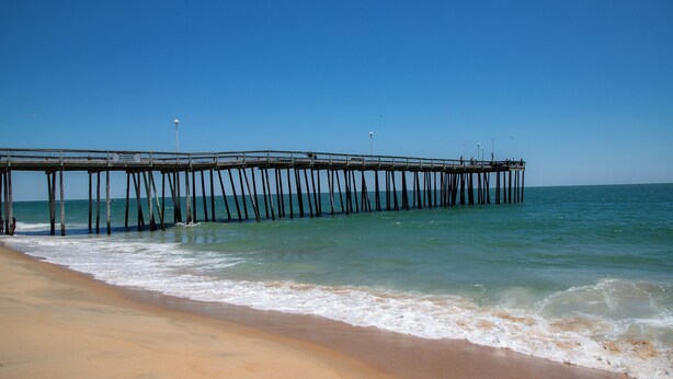A pier extending into the ocean with clear skies.