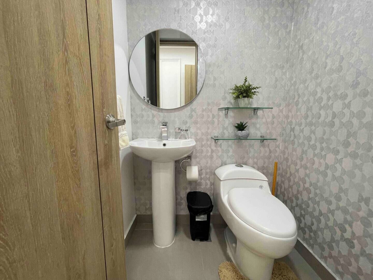 A bathroom with a wooden door, a white sink, a toilet, and a mirror.