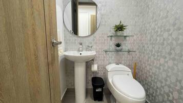A bathroom with a wooden door, a white sink, a toilet, and a mirror.
