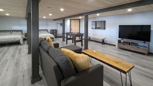 Een ruime kamer met een groot bed, een bank, een salontafel, een televisie en een tafelvoetbaltafel.