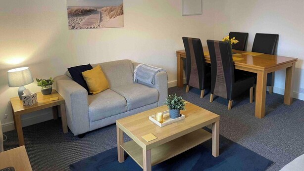 Een moderne woonkamer met een bank, salontafel en een eettafel met stoelen.
