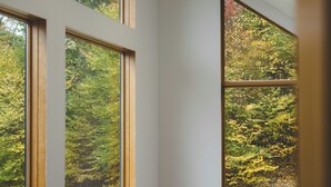 A room with large windows offering views of a forest.