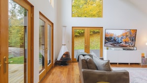 A spacious living room with a large TV, wooden flooring, and a fireplace.