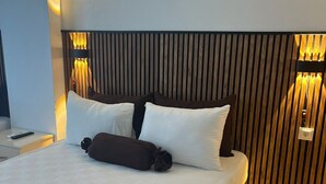 A neatly made bed with white and brown bedding, a wooden headboard, and a bedside table with a remote control. - Magarsus Elit Hotel (Karatas)