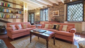 A cozy living room with a pink sofa, a wooden coffee table, and a bookshelf filled with books.