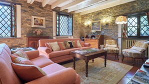 A cozy living room with a stone wall, a sofa, armchairs, a coffee table, and a fireplace.