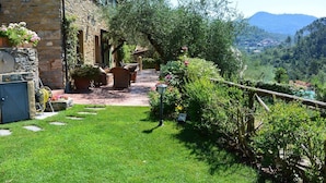 A stone building with a patio area, outdoor furniture, and a view of a mountainous landscape.