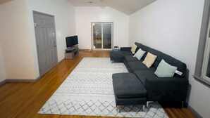 A modern living room with a sectional sofa, a flat-screen TV, and a patterned rug.