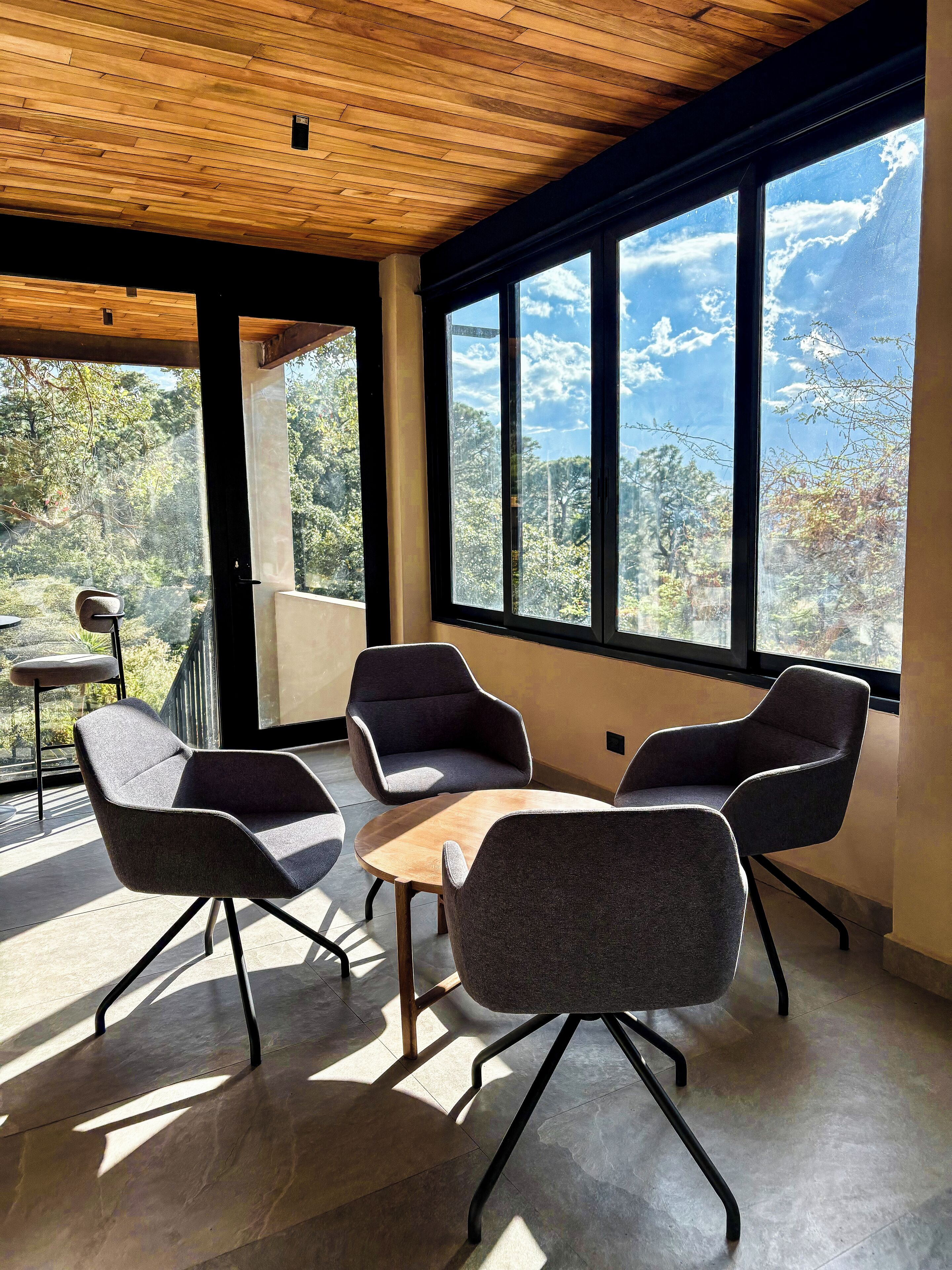 Un interior moderno con ventanas amplias, techo de madera y muebles contemporáneos.