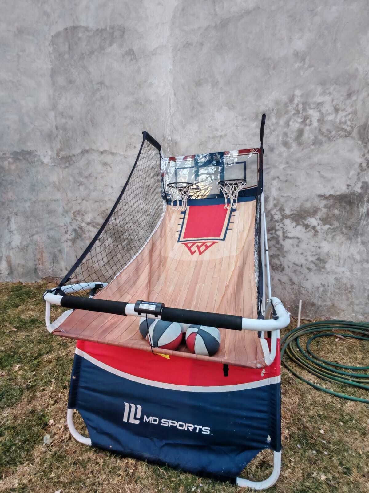 Un espace d’entraînement au basketball équipé d’un plancher en bois, d’un filet et de deux paniers de basketball.