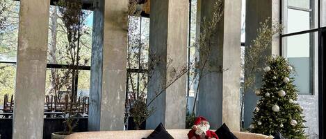 Un interior moderno con un sofá beige grande, taburetes de madera y un árbol de Navidad.