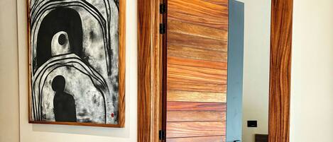 Una habitación con puerta de madera, una estructura metálica negra, un tapete estampado y una obra de arte abstracta en la pared.