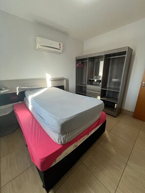 A hotel room with a bed, a wardrobe, and an air conditioning unit. - Fiore Prime (Caldas Novas)