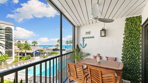 A balcony with a wooden table and chairs, a view of a pool, and a sign indicating a pool area.