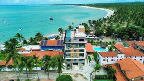 Un complejo turístico costero con edificios modernos, una piscina y vistas a la playa.