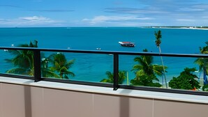 Un balcón con vista al océano y palmeras.