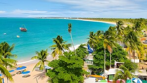 Una playa con aguas turquesas cristalinas, un bote y palmeras.