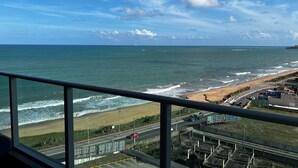 Blick auf die Küste von einem Hochhaus aus, mit Strand, Meer und blauem Himmel.