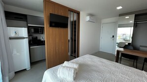 Ein Hotelzimmer mit einem Bett, einem Holzschrank, einer Küchenzeile und einem Badezimmer.