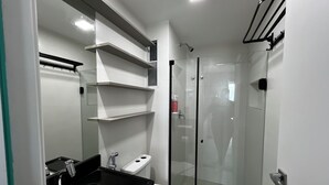 Ein modernes Badezimmer mit einer Duschkabine, einem schwarzen Waschtisch und weißen Armaturen.