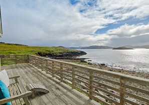 Relax on the deck with a serene view of the ocean and distant hills.
