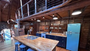 A rustic kitchen with a wooden island, bar stools, and a blue refrigerator. - 3 charming cottages sleeping 14 on an ocean cove, 21-acre forest property (Phippsburg)