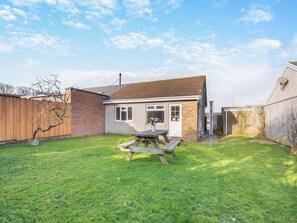 A house with a brick exterior, a wooden fence, a grassy yard, and a picnic table. - 3 bedroom accommodation in St Davids (St Davids)