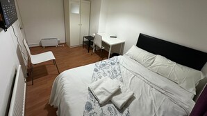 Una camera da letto con un letto, una scrivania, una sedia e un armadio.