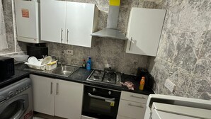 Una cucina compatta con mobili bianchi, fornello a gas, microonde e forno integrato.