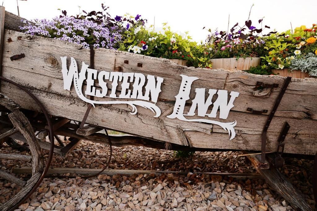 A wooden sign with the text "Western Inn" on a rustic background.