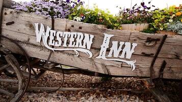 Uma placa de madeira com o texto "Western Inn" sobre um fundo rústico.