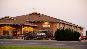 A Western Inn with a rustic exterior, a signboard, and a vintage wagon in front. - Western Inn (Tremonton)