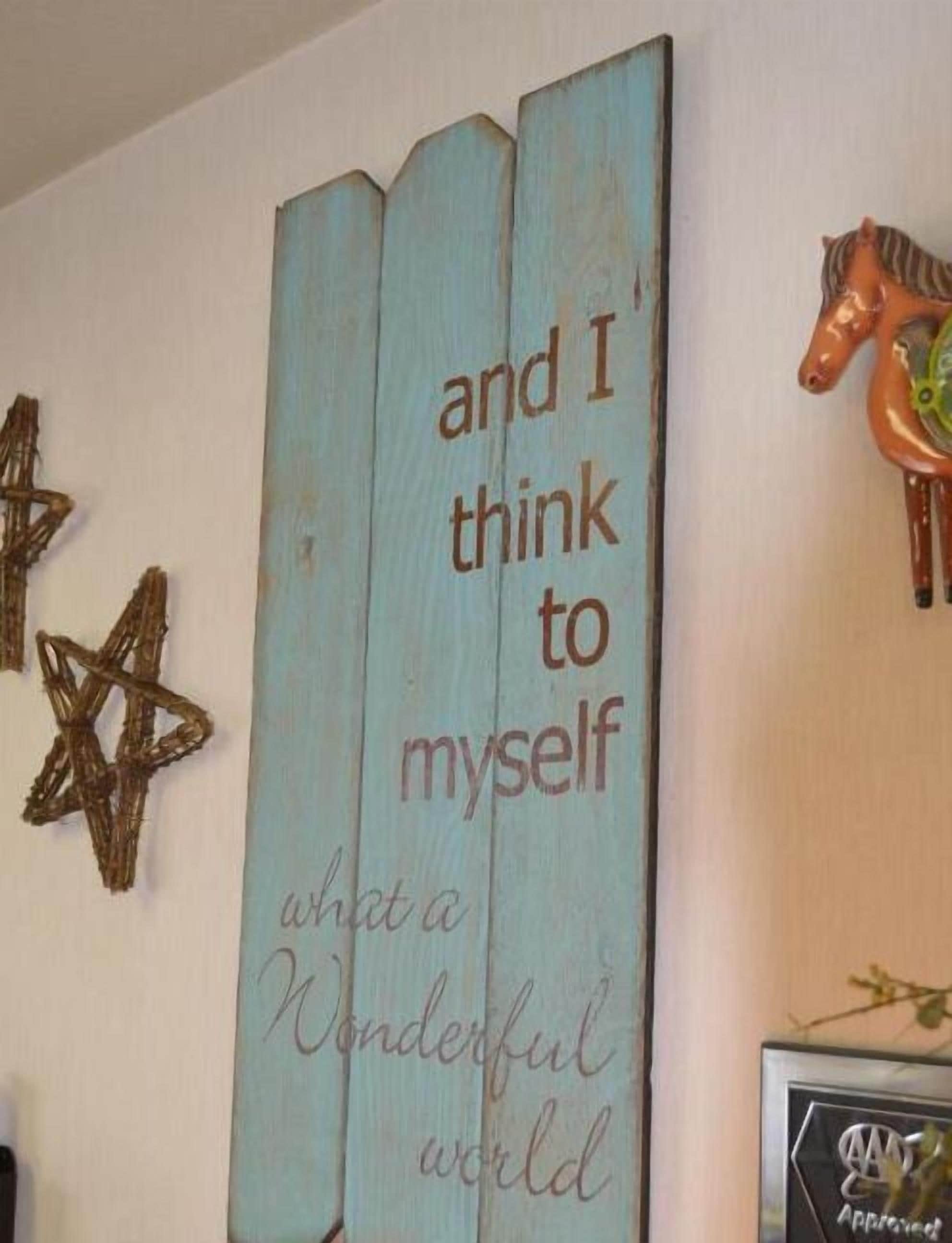 A wall with a wooden sign that reads "and I think to myself what a wonderful world" and a decorative horse figure.