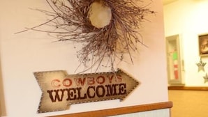 A wall with a 'Cowboys Welcome' sign and a 'Give Thanks' sign on a barrel. - Western Inn (Tremonton)