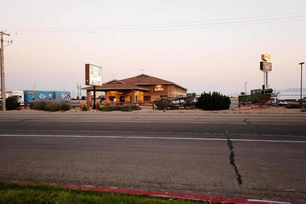 A Western Union building with a large sign, a gas station, and a vintage tractor on the roadside.