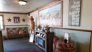 A lobby with a wooden bench, a statue, a framed painting, and a barrel. - Western Inn (Tremonton)