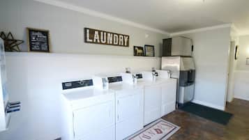 A laundry area with a wall-mounted sign reading "LAUNDRY," a stainless steel refrigerator, and a set of white laundry machines.