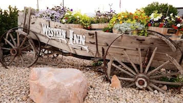 A rustic wooden sign with "WESTERN INN" written on it, surrounded by colorful flowers and a large rock.
