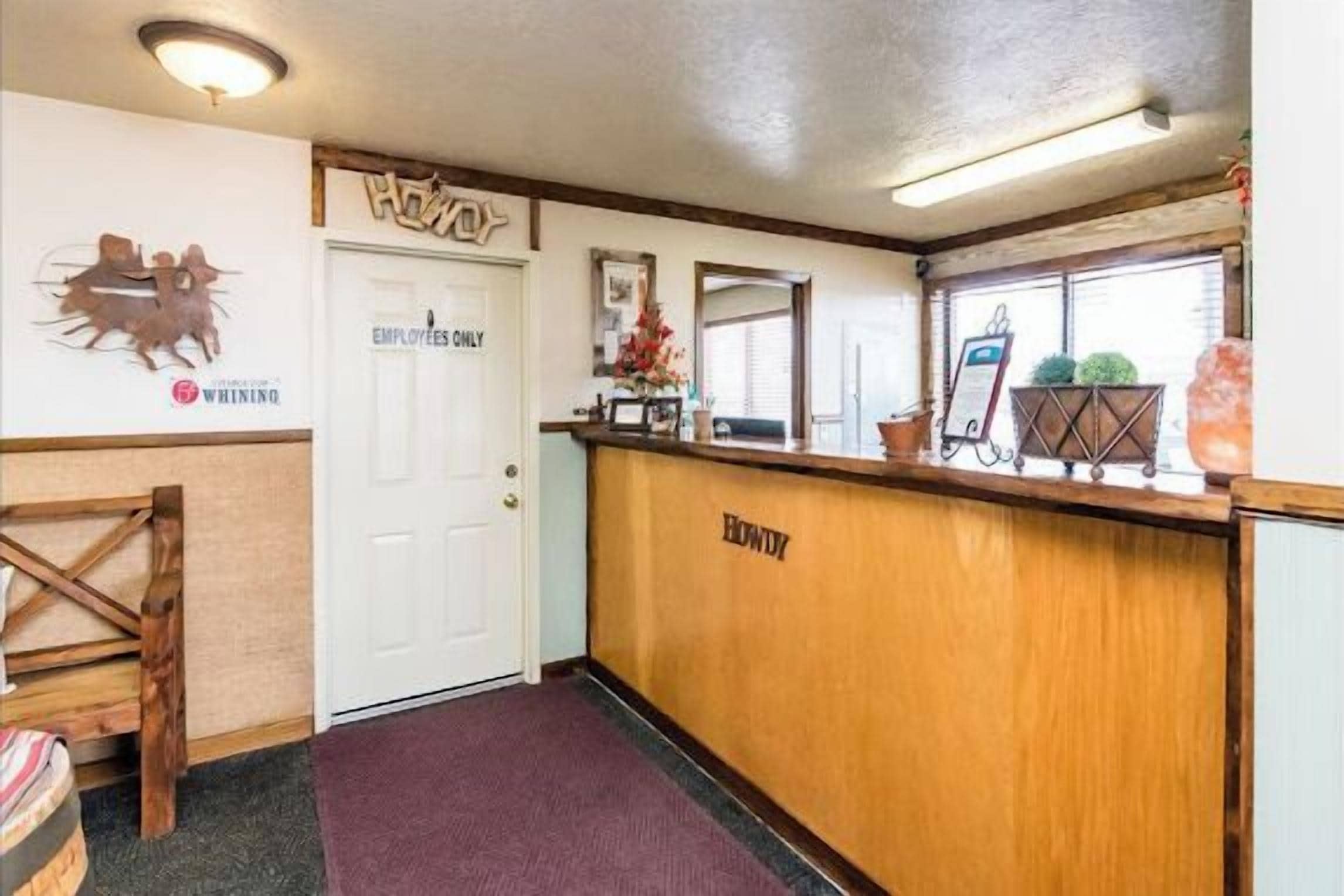 A reception area with a wooden counter, a reception desk, and a door labeled "EMPLOYEES ONLY".