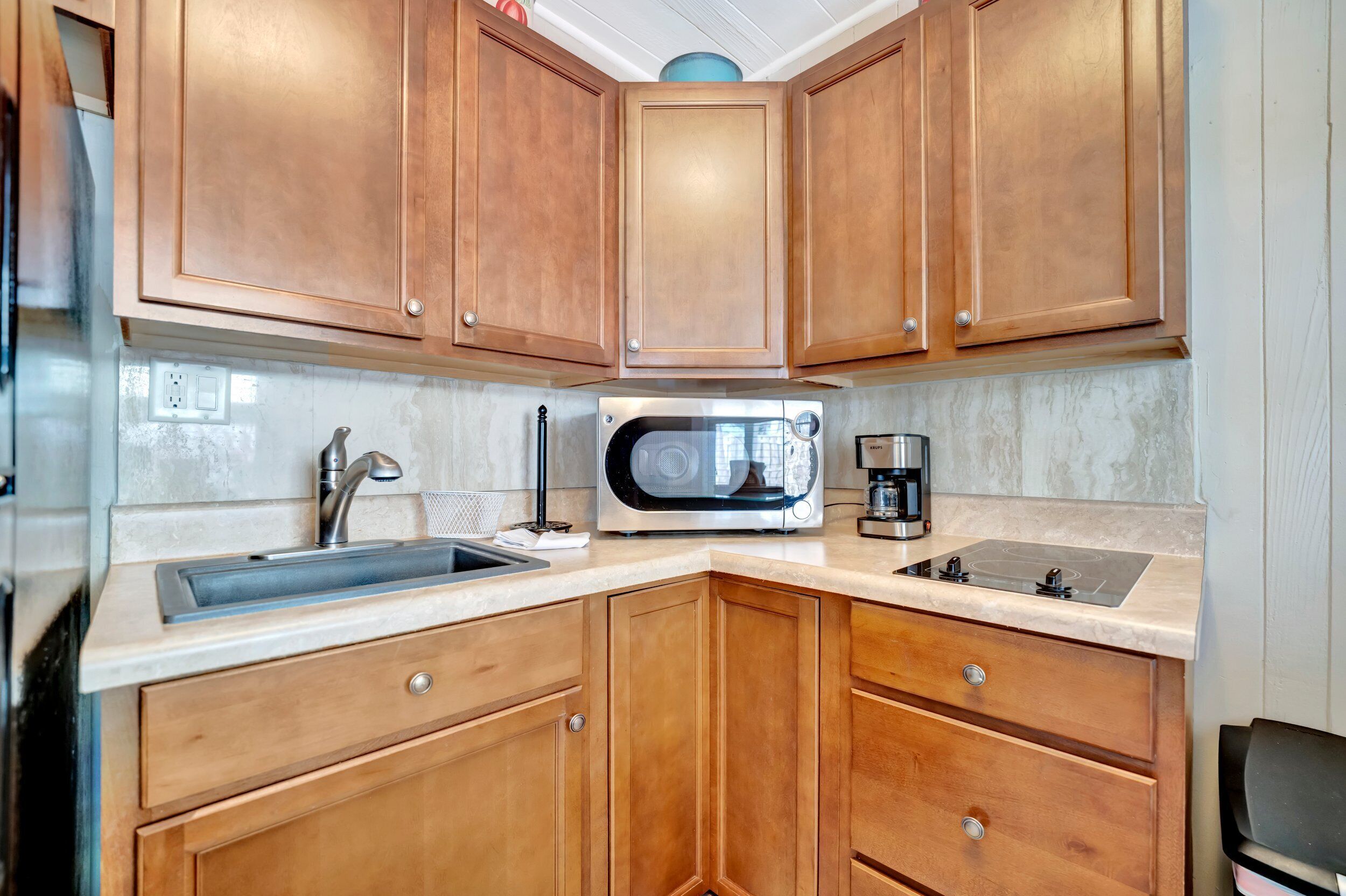 A kitchen with wooden cabinets, a sink, a microwave, and a coffee maker.