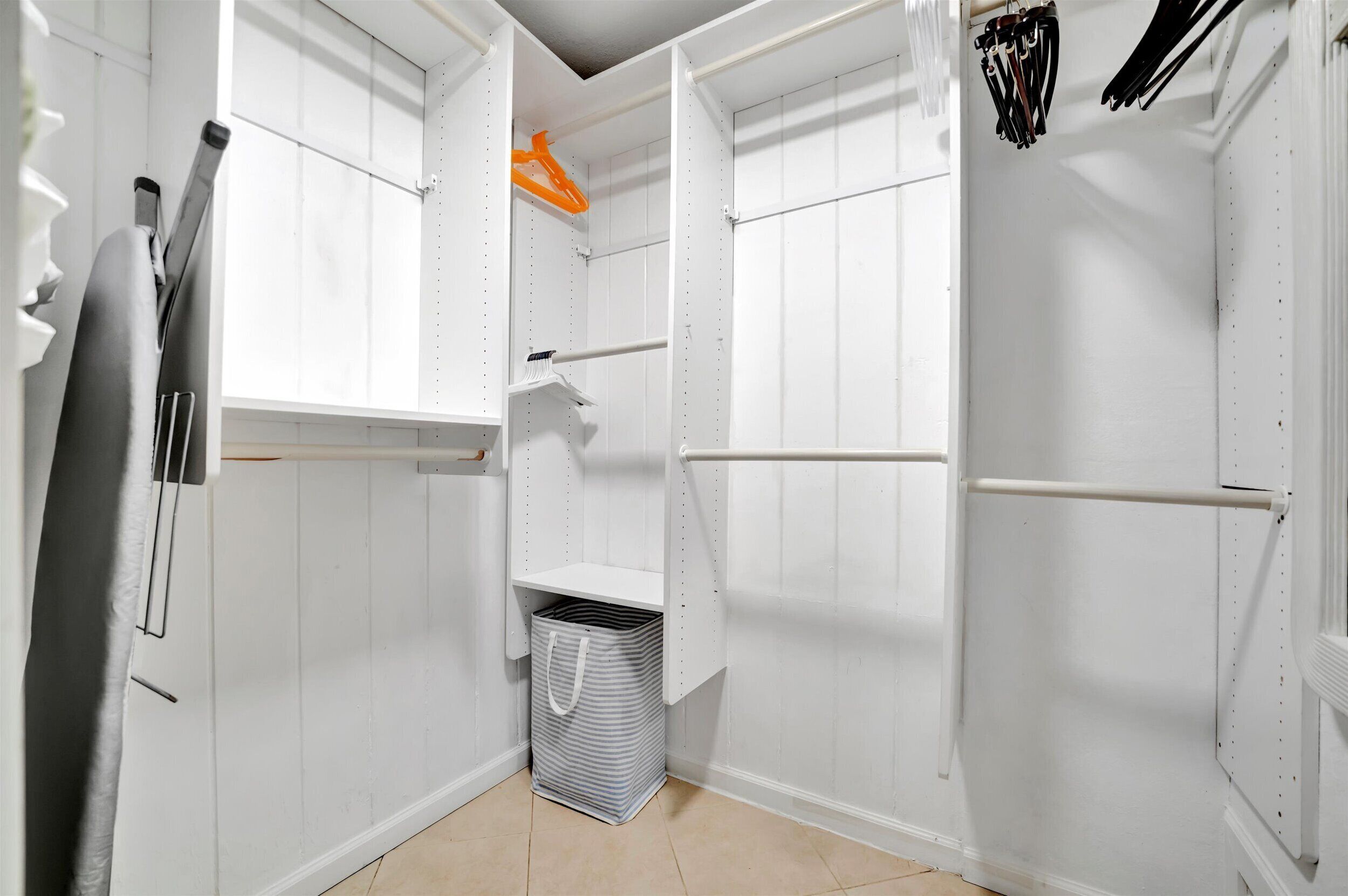 Een witte kast met geopende deuren, waar planken en een kledingroede zichtbaar zijn.